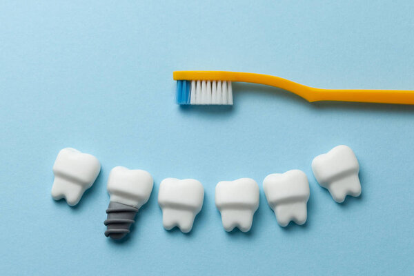 Healthy white teeth and implants on blue background with toothbrush