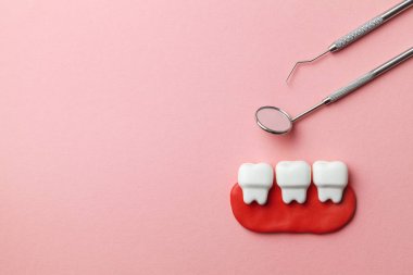 Pembe arka plan ve dişçi araçları ayna, kanca sağlıklı beyaz dişler. Metin için boşluk Kopyala.