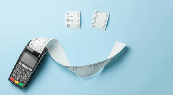 Terminal registratore di cassa POS per i pagamenti e lungo rotolo di carta nastro di cassa a forma di sorriso su sfondo blu . — Foto Stock