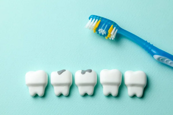 Dentes brancos saudáveis e dente com cárie em fundo de hortelã verde e escova de dentes . — Fotografia de Stock