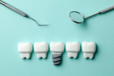 Sağlıklı beyaz dişler ve implantlar yeşil nane arka plan ve diş hekimi araçları ayna, kanca.