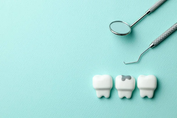 Υγιή λευκά δόντια και δόντι με τερηδόνα σε πράσινο Νομισματοκοπείο και εργαλεία οδοντίατρου καθρέφτη, γάντζος. Αντιγραφή χώρου για κείμενο. — Φωτογραφία Αρχείου