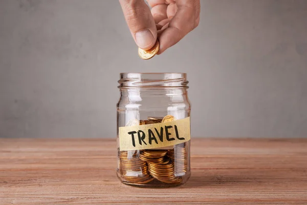 Travel. Glass jar with coins and an inscription travel. Man holds  coin in his hand — Stock Photo, Image