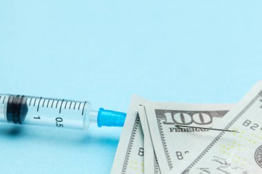 Şırınga ve kağıt dolar mavi arka planda iğne sabitlenmiş. Pahalı tıbbi sigorta. Metin için boşluk Kopyala.