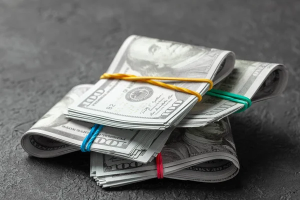 Pilhas de dólares em dinheiro amarrado com bandas de escritório coloridas em fundo escuro. Conceito de poupança ou suborno — Fotografia de Stock