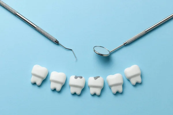 Fehér fogak fogszuvasodás, a kék háttér és a fogorvos eszközöket tükör, kampó. — Stock Fotó