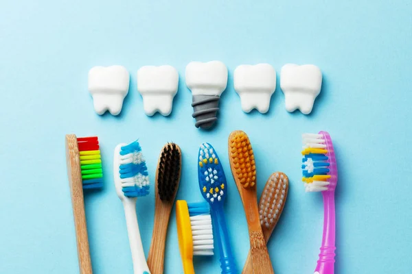 Healthy white teeth and implants on blue background with toothbrush — Stock Photo, Image