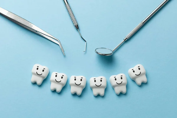 Здорові білі зуби посміхаються на синьому фоні, а інструменти стоматолога дзеркало, гачок . — стокове фото