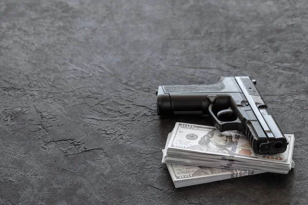 Pistol and money. Guns and dollars on black background. Copy space for text.
