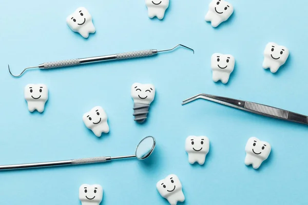 Dents blanches saines et des implants sourient sur fond bleu et des outils de dentiste miroir, crochet . — Photo