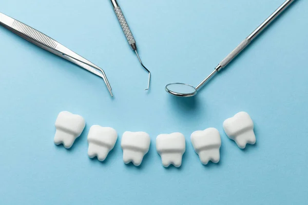 Egészséges, fehér fogak kék háttér-és fogorvosi eszközök tükör, horog. — Stock Fotó