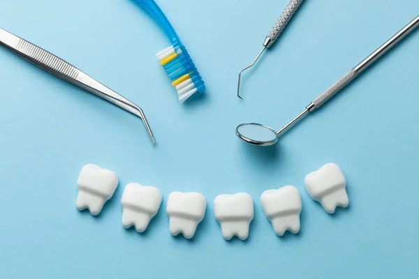 Dents blanches saines sur fond bleu et outils de dentiste miroir, crochet . — Photo