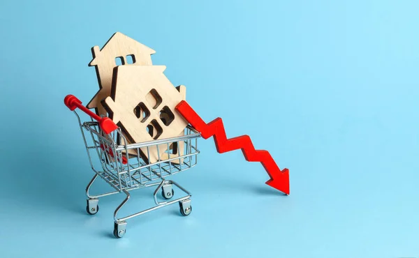 Arrow to down and houses in shopping cart on blue background. Market growth in real estate prices — Stock Photo, Image