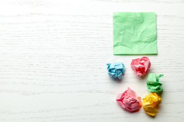 Beyaz ahşap masa üzerinde renkli buruşuk not kağıdı. Metin için alan kopyalama.