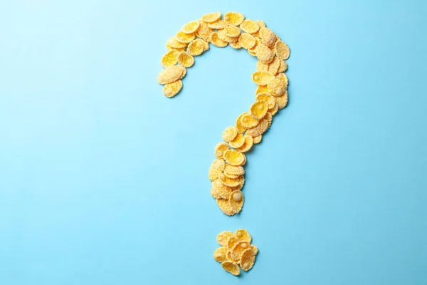 Copos amarillos en forma de signo de interrogación sobre un fondo azul. Cómo elegir el cereal para el desayuno o lo que hacen los cereales . — Foto de Stock