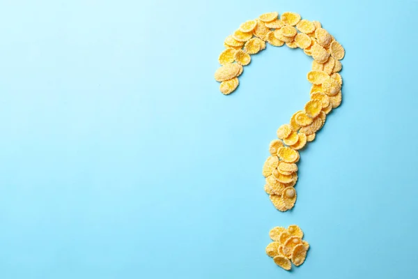 Copos amarillos en forma de signo de interrogación sobre un fondo azul. Cómo elegir el cereal para el desayuno o lo que hacen los cereales. Copiar espacio para texto . — Foto de Stock