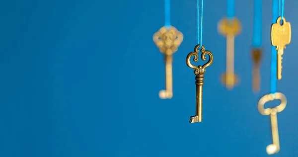 Muitas chaves antigas de cor de ouro amarelo estão penduradas no fio em um fundo azul. O conceito da seleção de acesso ou senha para os dados secretos. Espaço de cópia para texto . — Fotografia de Stock