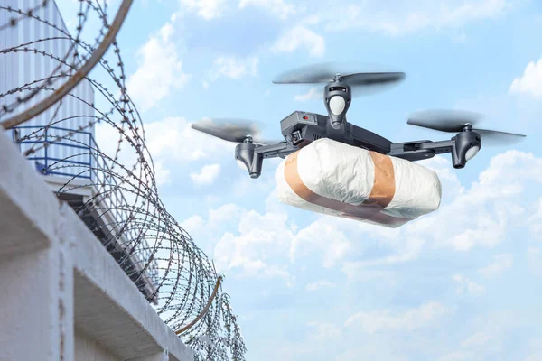 The drone flew across the sky with smuggling. The drone transports forbidden goods across the border breaking the law. Delivery of drugs through the wall with barbed wire