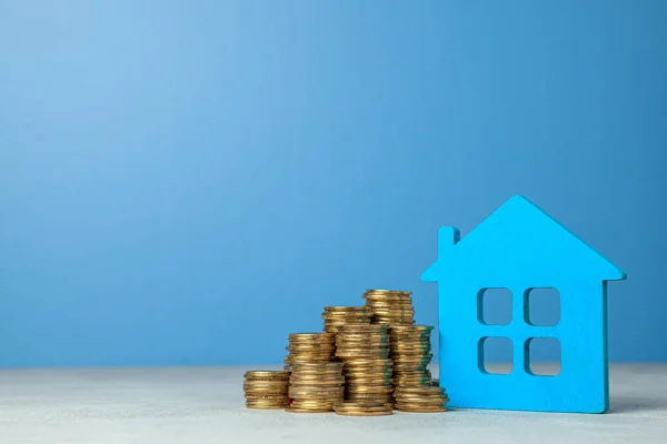 Casa y pila de monedas. El concepto de comprar una casa o un seguro. Fondo azul . — Foto de Stock