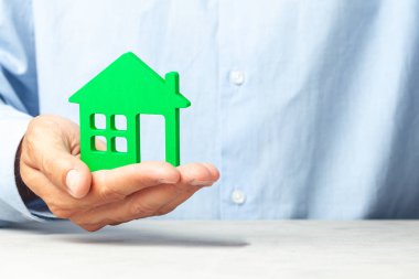 Mavi gömlekli adam elinde ev tutuyor. Concept emlakçı ev veya gayrimenkul kredisi satın almak için teklifler