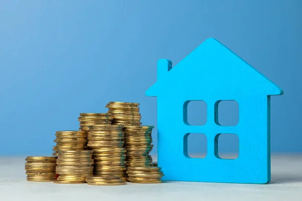 Casa y pila de monedas. El concepto de comprar una casa o un seguro. Fondo azul . — Foto de Stock