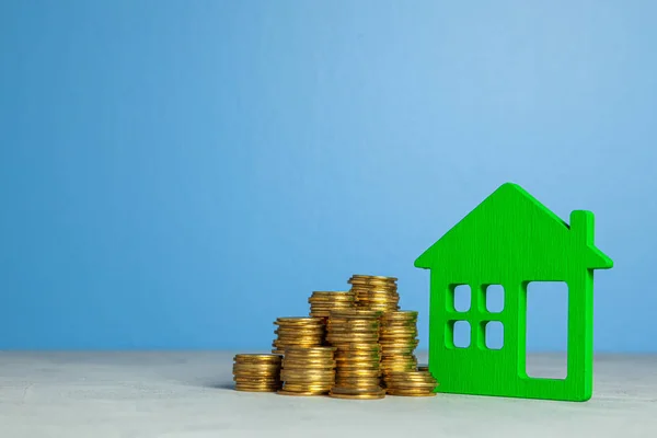 Casa y pila de monedas. El concepto de comprar una casa o un seguro. Fondo azul. Copiar espacio para texto . — Foto de Stock