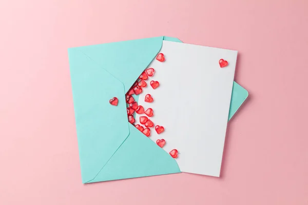 Love letter with red hearts. Blank template with place for text on postcard. Green envelope on pink background. mock-up