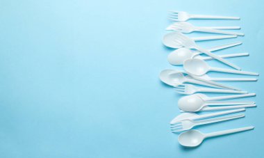Plastik çatal, çatal, kaşık ve bıçaklar. Plastik ve mikroplastiklerle çevre kirliliği. Mavi arka plan. Metin için alanı kopyala.