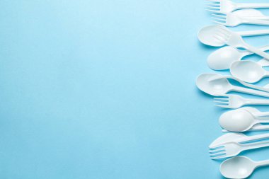 Plastik çatal, çatal, kaşık ve bıçaklar. Plastik ve mikroplastiklerle çevre kirliliği. Mavi arka plan. Metin için alanı kopyala.