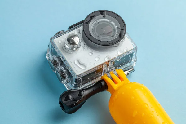 Action camera in a waterproof box and a buoy for diving in water drops on a blue background