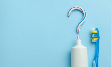 Diş macunundaki soru işareti. Diş beyazlatma için iyi diş macunu seçimi. Mavi arka planda renkli diş macunu ve diş fırçası tüpü. Metin için alanı kopyala.