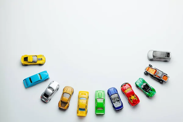 Багато кольорових маленьких іграшкових автомобілів на сірому фоні . — стокове фото