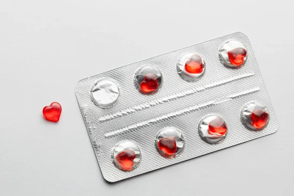 Love pills. Blister pack with red heart shaped pills. Tablets for lovers or potency. Gray background — Stock Photo, Image