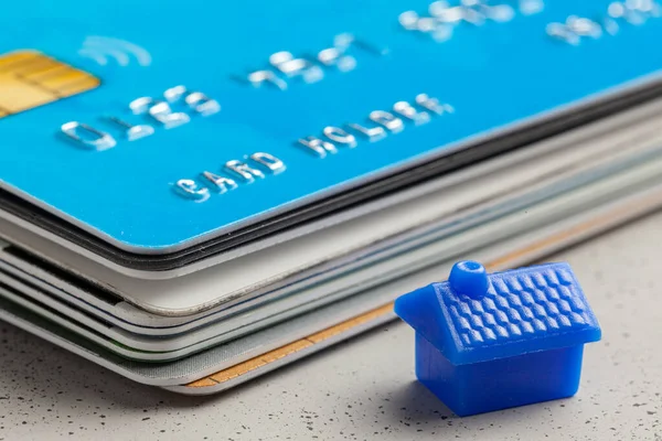 Casa y tarjeta de crédito en gris. El concepto de comprar una casa a crédito o pagar facturas de servicios públicos . — Foto de Stock