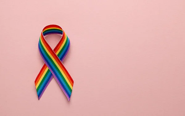Ruban arc-en-ciel LGBT symbole de ruban de fierté. Arrêtez l'homophobie. Fond rose. Espace de copie pour le texte. — Photo