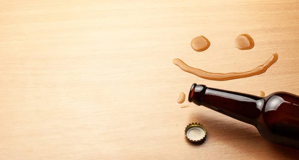 Bier lächelt. Bierflasche und verschüttetes Getränk auf dem Tisch. Kopierraum für Text. — Stockfoto