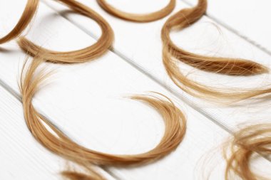 Beyaz ahşap arka planda saç bukleleri kes