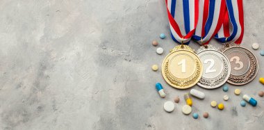 Sporcular için doping. Altın, gümüş ve bronz madalya ve gri arka planda kapsüllü haplar.