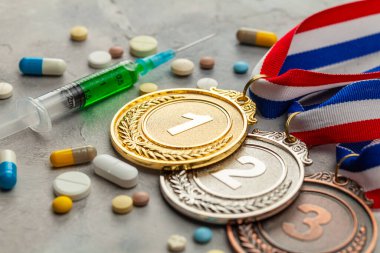 Sporcular için doping. Altın, gümüş ve bronz madalya ve doping şırıngası ve gri kapsüllü haplar