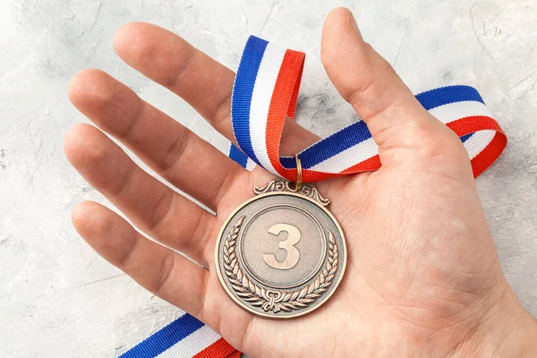 Χάλκινο μετάλλιο. Ένας άνθρωπος κατέχει ένα τρίτο βραβείο θέση με μια κορδέλα στο χέρι του — Φωτογραφία Αρχείου