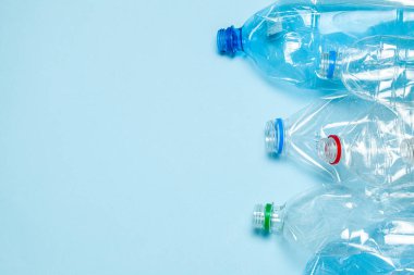 Mavi arka planda buruşmuş plastik şişeler. Plastik çöp. Metin için alanı kopyala.