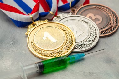 Sporcular için doping. Altın, gümüş ve bronz madalya ve gri arka planda doping şırıngası