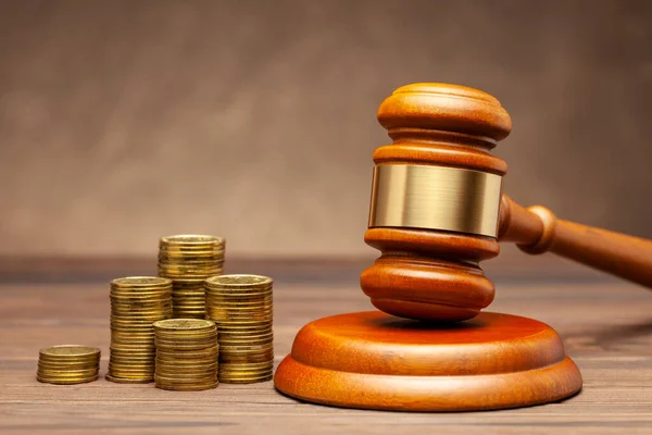 Stapel von Münzen und Richtergabel auf braunem Hintergrund. Das Konzept der Nichtzahlung von Steuern — Stockbild Stapel von Münzen und Richtergabel auf braunem Hintergrund. Das Konzept der Nichtzahlung von Steuern. — Stockfoto