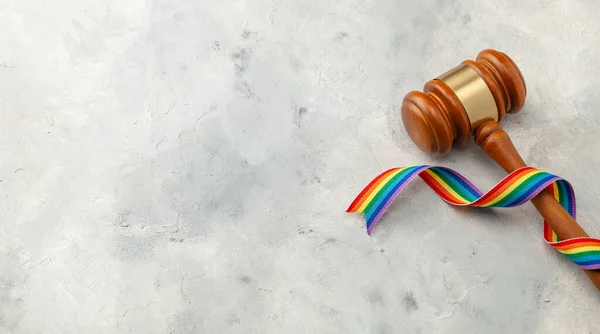 灰色の背景にLGBTの誇りの裁判官のギャベルと虹のリボン。テキストのコピースペース — ストック写真