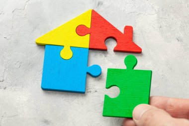 Ev bulmacası ev kredisi. Evin parçaları bir araya getirildi. Erkek el yapboz parçasını tutuyor