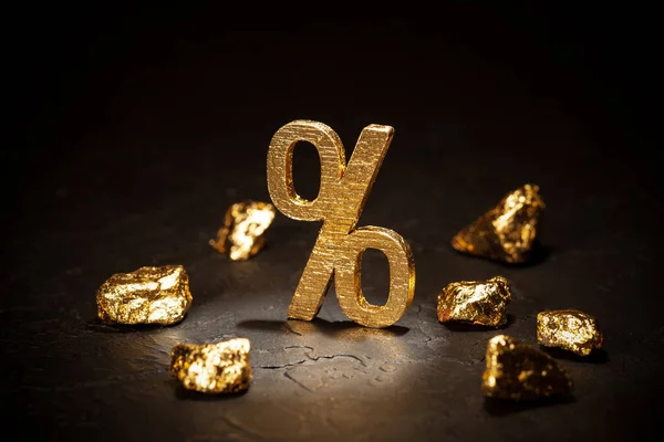 Gold percent sign and gold nuggets on black background