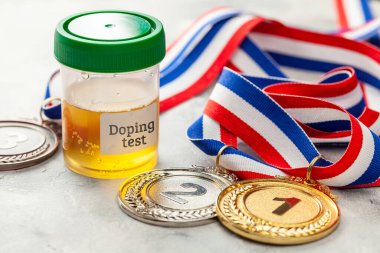 Doping testi. Altın, gümüş ve bronz madalya ve gri arka planda idrar analizi için bir kavanoz.