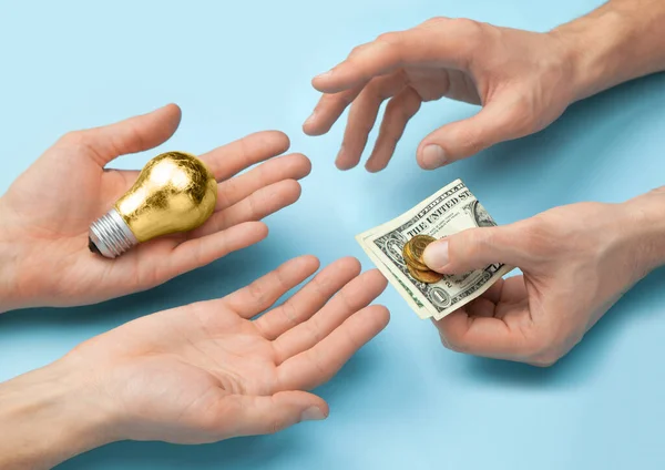 Selling ideas for money. Light bulb as a symbol of idea. Hands of a man give an idea and take money
