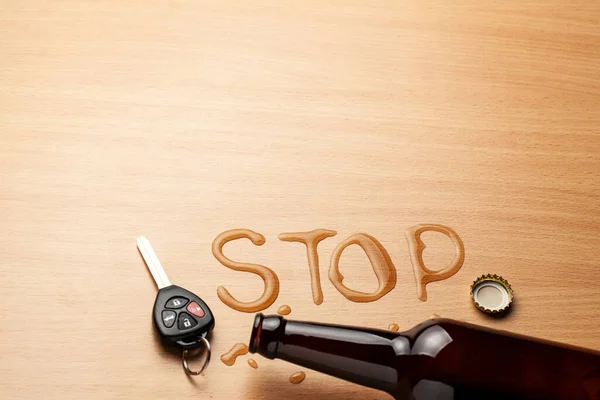 П'яний водій. Пивна пляшка і розлите пиво у формі слова STOP. Автомобільні ключі — стокове фото