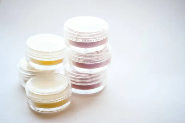 jars with colored cosmetic lip balm on a light background, lip care
